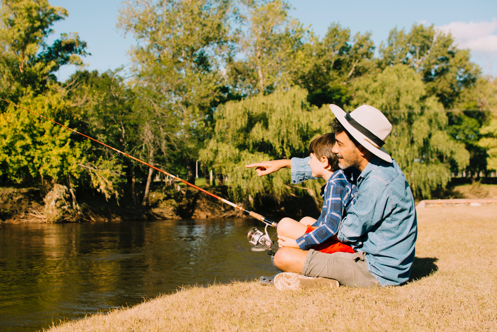 Father and son fishing together by the riverbank