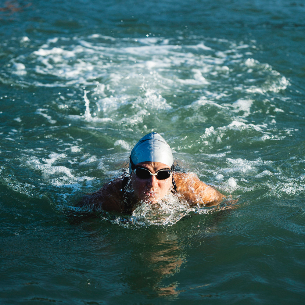 Swimmer in goggles and cap swimming in open sea