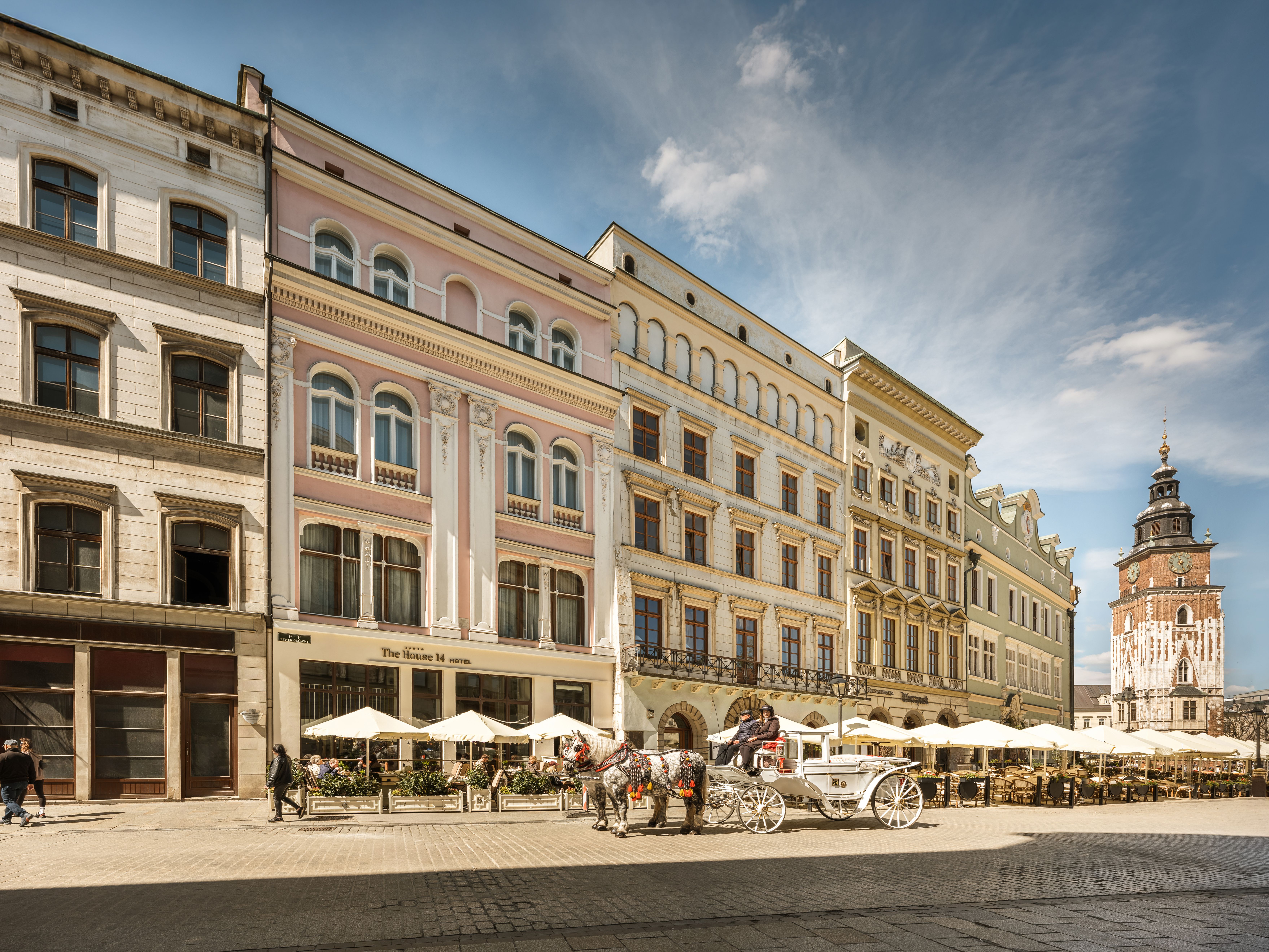 Historic Main Square facade of The House 14 Hotel with a horse-drawn carriage out front