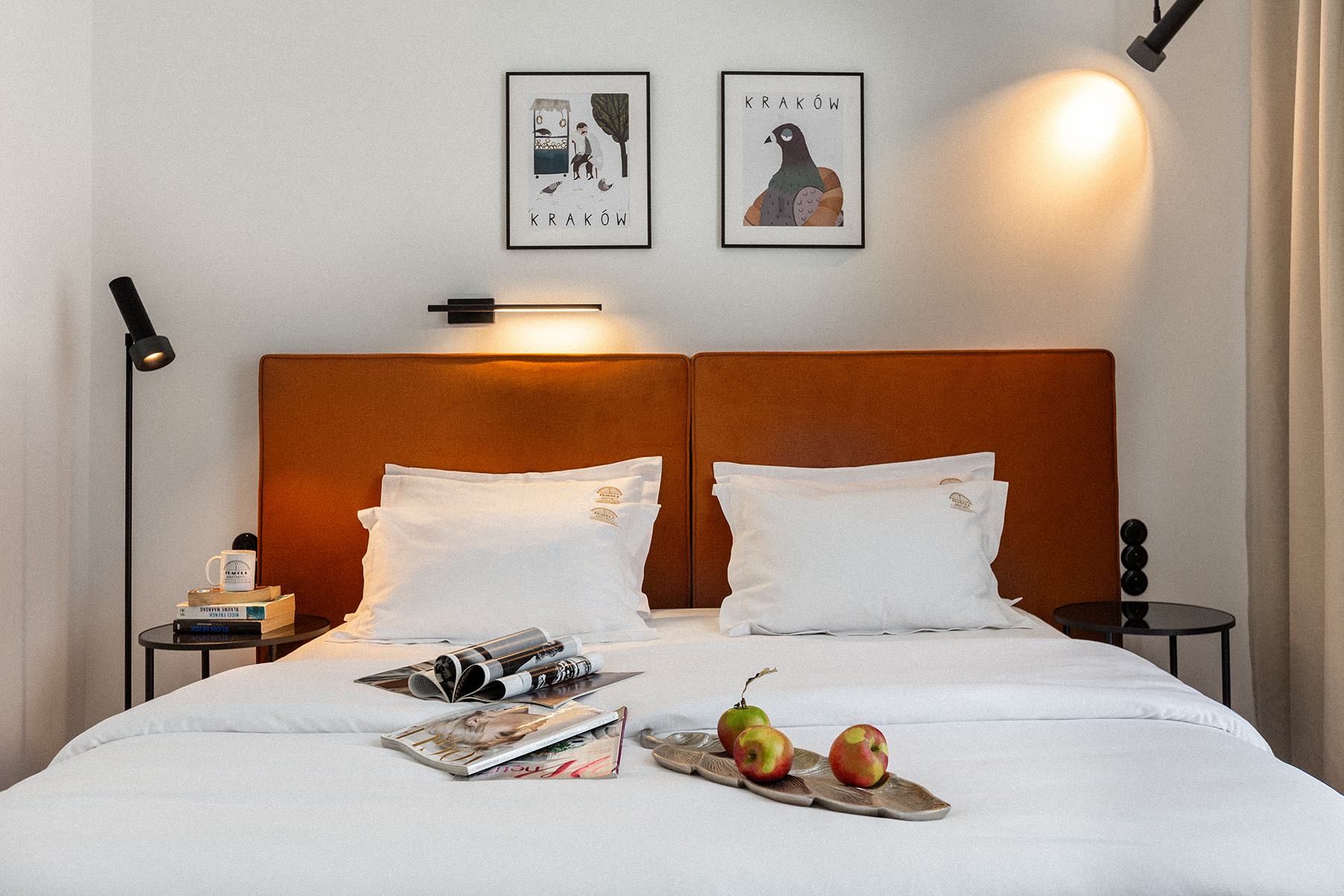 Bedroom with rust-colored velvet headboard and Kraków-themed art prints