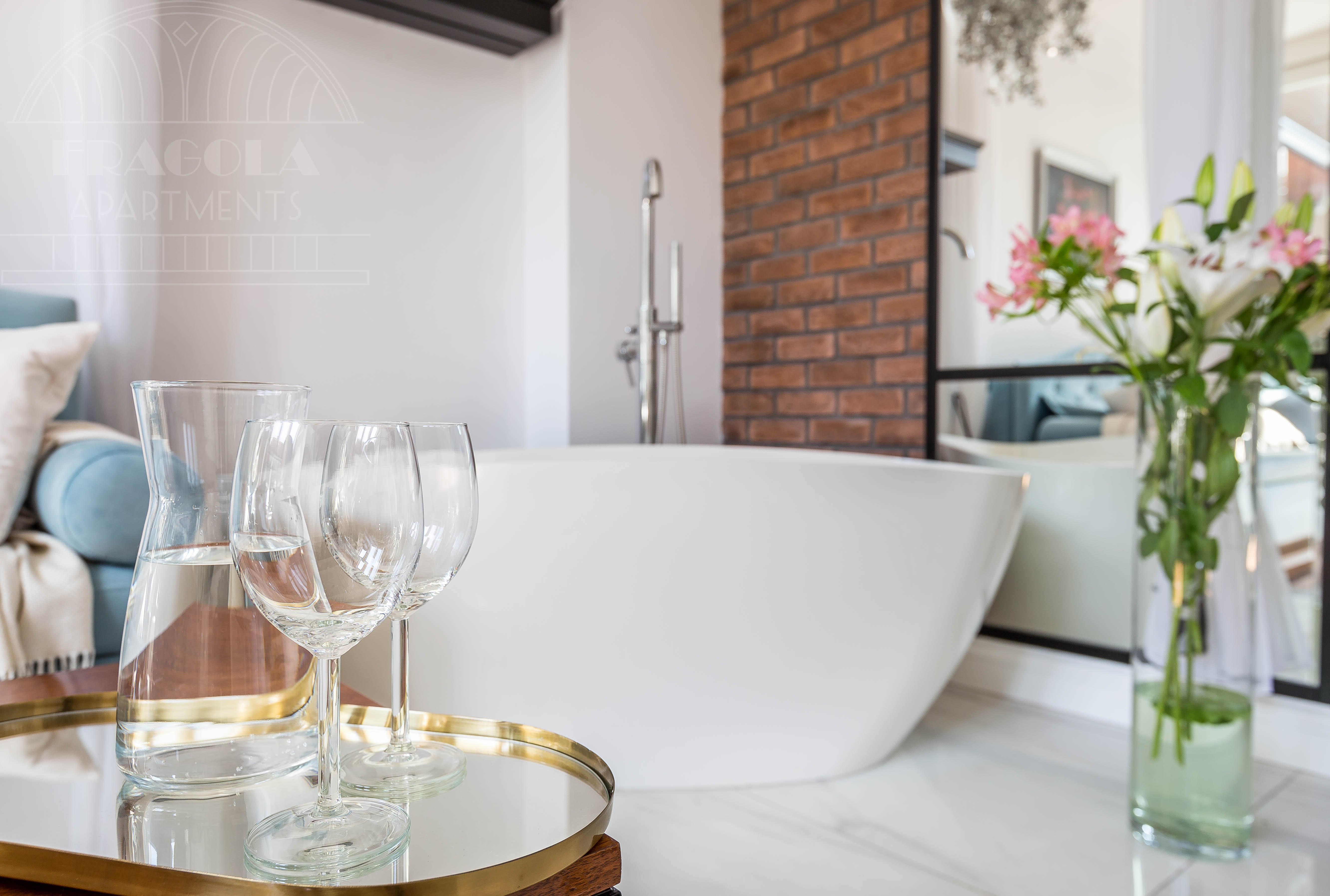 Freestanding bathtub with wine glasses and fresh flowers